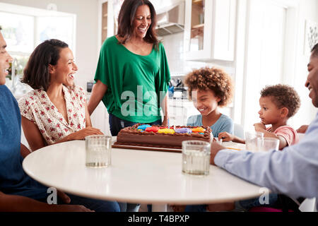 Tre generazioni della famiglia razza mista famiglia riunita attorno al tavolo della cucina celebra il pre-teen figlia il compleanno con una torta di compleanno Foto Stock