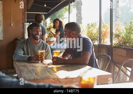 Due maschi amici riuniti in Sports Bar godendo di bere prima del gioco Foto Stock