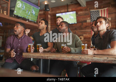 Gruppo di amici maschi la visione di gioco sullo schermo in Sports Bar Foto Stock