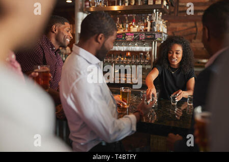 Barista serve scatti di gruppo di amici maschi sulla notte fuori in bar Foto Stock