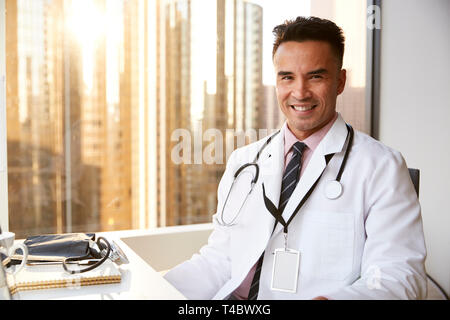 Ritratto di sorridente medico maschio indossa mantello bianco con uno stetoscopio in ospedale Office Foto Stock