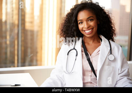 Ritratto di sorridere medico donna indossa mantello bianco con uno stetoscopio in ospedale Office Foto Stock