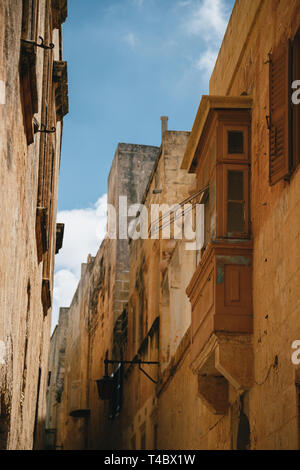 Giallo strette strade medievali con tipico balcone maltese in Mdina, antica capitale di Malta, città medievale fortificata. Popolare destinazione turistica Foto Stock