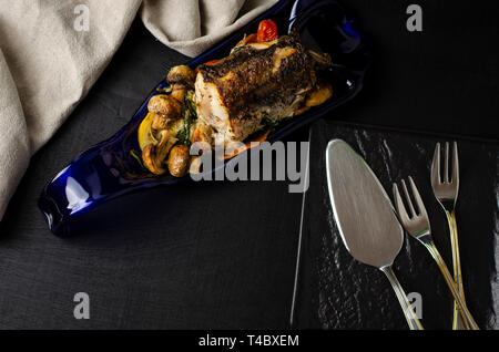 Arrosto di nasello pesce con verdure su una piastra di colore blu su sfondo nero. Una sana alimentazione e dieta cheto concetto. Vista dall'alto. Spazio di copia Foto Stock