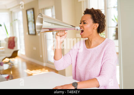 Giovani belle americano africano donna con capelli afro urlando utilizzando megafono Foto Stock