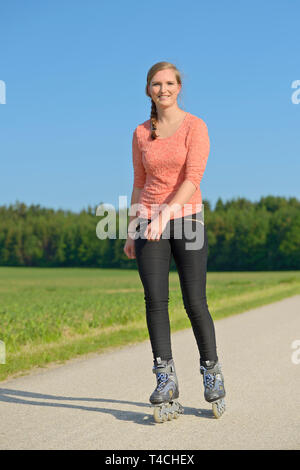 Giovane donna con i rollerblade su una piccola strada. Foto Stock