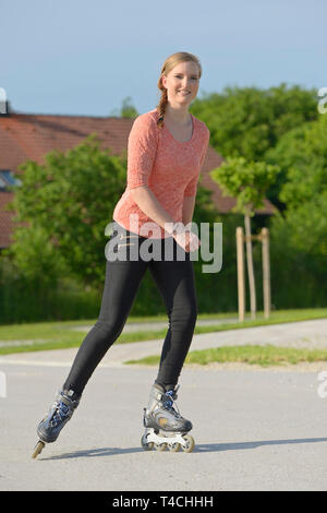 Giovane donna con i rollerblade su una piccola strada Foto Stock