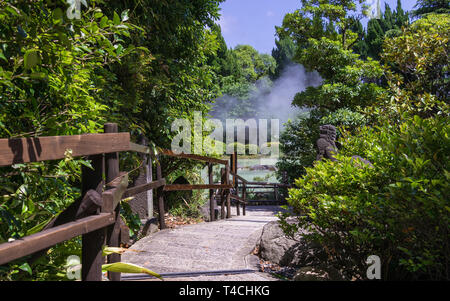 Percorso di Nizza, con vegetazione verde e giardino. Nelle famose sorgenti calde geotermali, chiamato Shiraike Jigoku, engl. bianco stagno inferno,. Beppu, Oita, Giappone Foto Stock