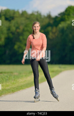 Giovane donna con i rollerblade su una piccola strada. Foto Stock