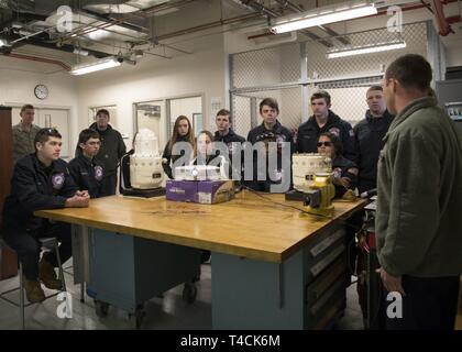 Gli studenti di aviazione da Westfield Accademia Tecnica appreso su un drive integrato e generatore di corrente alternata di alimentazione dei generatori di sistemi da Tech. Sgt. Bryan McFarlandf, 104th gruppo Manutenzione elettrica e sistemi ambientali tecnico di manutenzione, durante un tour 19 marzo 2019, presso Barnes Air National Guard Base, Massachusetts. Tredici studenti provenienti da Westfield Accademia tecnica acquisita una comprensione più profonda dei sistemi idraulici ed elettrici e sistemi ambientali negozi presso il 104th Fighter Wing durante il tour. Foto Stock