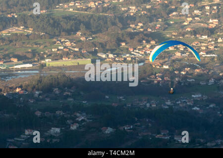 Persona in volo in parapendio sopra una piccola città Foto Stock