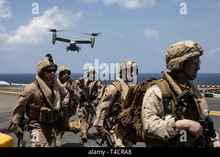 Golfo di Aden (23 marzo 2019) - USA Marines con il ventiduesimo Marine Expeditionary Unit partono il ponte di volo come un MV-22 Osprey si prepara a terra a bordo Wasp-classe assalto anfibio nave USS Kearsarge (LHD-3) durante una tattica di recupero di aeromobili e di missione del personale prove. Il corso di formazione prepara Marines per inserire aree combattivo e recuperare o distruggere i materiali sensibili nonché recuperare personale. Marines e marinai con il ventiduesimo MEU e anfibio Kearsarge pronto Gruppo sono attualmente dispiegati per gli Stati Uniti Quinta Flotta area di operazioni a sostegno di operazioni navali per garantire maritime st Foto Stock