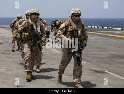 Golfo di Aden (23 marzo 2019) - USA Marines con il ventiduesimo Marine Expeditionary Unit a piedi verso il basso il ponte di volo di wasp-classe assalto anfibio nave USS Kearsarge (LHD-3) dopo l'uscita di un MV-22 Osprey durante una tattica di recupero di aeromobili e di missione del personale prove. Il corso di formazione prepara Marines per inserire aree combattivo e recuperare o distruggere i materiali sensibili nonché recuperare personale. Marines e marinai con il ventiduesimo MEU e anfibio Kearsarge pronto Gruppo sono attualmente dispiegati per gli Stati Uniti Quinta Flotta area di operazioni a sostegno di operazioni navali per garantire stabi marittima Foto Stock