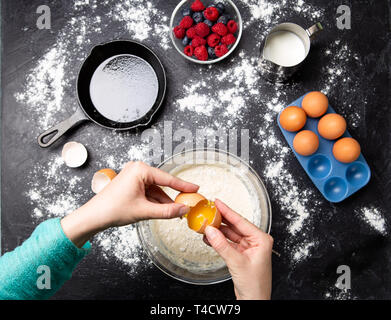 Foto di mani di uomo rompere le uova in una terrina. Ingredienti per frittelle. Foto Stock