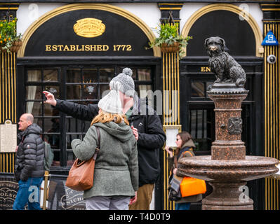 Turista giovane indossando cappelli bobble tenendo selfie con Grayfriar Bobby della statua del cane, Edimburgo, Scozia, Regno Unito Foto Stock