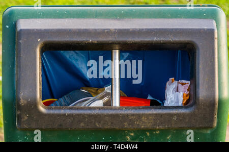 Primo piano della apertura di un cestino della spazzatura nel parco, consapevolezza ambientale, sullo sfondo di riciclo Foto Stock
