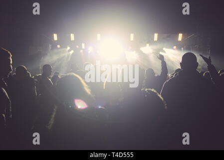 Persone con retroilluminazione al concerto e forte faretti Foto Stock