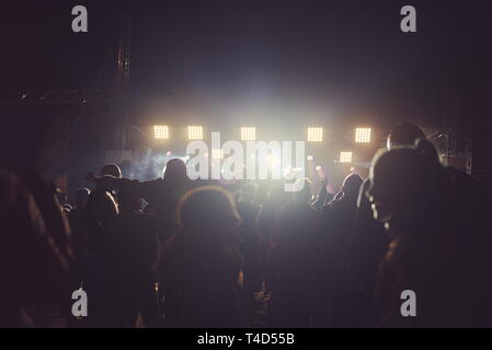 Persone con retroilluminazione al concerto e forte faretti Foto Stock