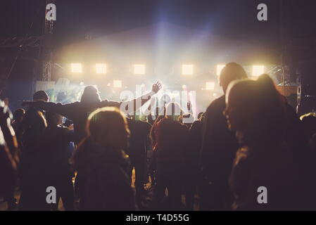 Persone con retroilluminazione al concerto e forte faretti Foto Stock