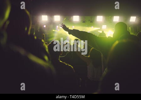 Persone con retroilluminazione al concerto e forte faretti Foto Stock