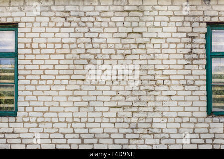 Old Dirty incrinato bianco parete in mattoni con retro finestre in legno dal lato. Grigio sfondo a trama. Foto Stock