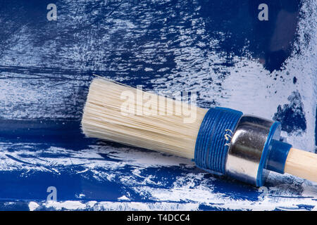Bianco pittore rotonda pennello in un vecchio pittore blu contenitore Foto Stock