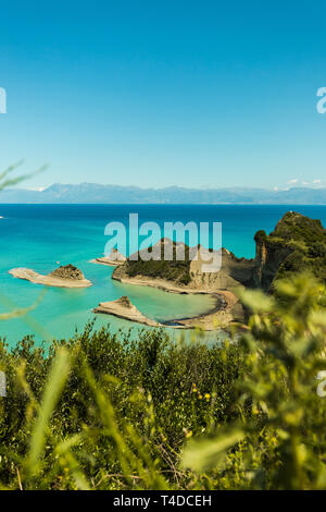 Cape Drastis (Perulades) con acque blu cristallo del mare su una soleggiata giornata estiva come visto da un punto più alto con l'Albania in background (Corfù) Foto Stock