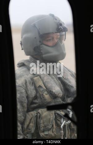 Spc. Aaron Winberg, UH-60 Blackhawk elicottero membro di equipaggio, guarda il suo velivolo durante la fase di avvio, prima di volare operazione flood, in Lincoln Marzo 23. Il Nebraska aviation equipaggi sono state assistendo con missioni sandbagging sul fiume Loup a partire dalla metà di marzo. (Nebraska Guardia Nazionale Foto Stock