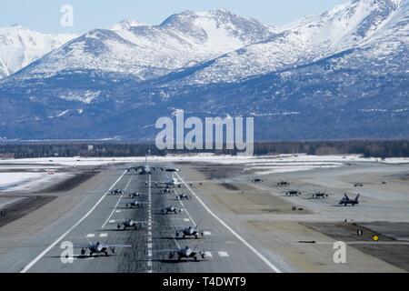 F-22 rapaci dalla terza ala e 477th Fighter Group partecipa in una stretta formazione taxi con un'E-3 Sentry e UNA C-17 Globemaster III, noto come un elefante a piedi, 26 marzo 2019, durante una forza polare esercizio a base comune Elmendorf-Richardson, Alaska. Questa due settimana di esercizio squadroni dà la possibilità di dimostrare la loro capacità di trasmettere la distribuire e fornire schiacciante combattere airpower. Foto Stock