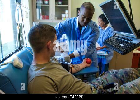 FORT BENNING, Ga. -- Il personale Sgt. Jemiah Daniels, al centro di un tecnico di laboratorio con il Sullivan Memorial Blood Center, tamponi iodio sul braccio di Pvt. Tyler Griggs, un soldato di fanteria, in preparazione del prelievo del sangue da Griggs. Dei militari e del personale civile degli Sullivan Memorial Blood Center si trova a Fort Benning informato manovra Centro di Eccellenza Comandante Generale Il Mag. Gen. Gary M. Brito sui contributi del centro e le capacità in relazione alle Forze Armate Programma di sangue durante la sua visita alla struttura 22 Marzo 2019. Il ASBP è ufficiale la raccolta di sangue, la fabbricazione Foto Stock