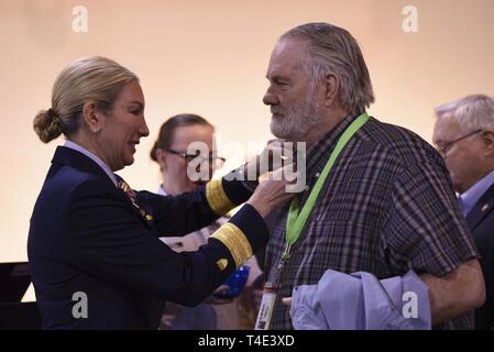 Stati Uniti La guardia costiera Adm posteriore. Melissa Bert vincola una guerra del Vietnam commemorazione pin su un veterano durante un risvolto pinning cerimonia al Navy Yard a Washington D.C., Marzo 29, 2019. Reduci dal servizio di tutti i rami sono stati presenti a riconoscere il Vietnam nazionale veterani di guerra al giorno. Stati Uniti Coast Guard Foto Stock