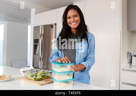 Ritratto di donna in cucina la preparazione di alta farina proteica e porzioni di messa in contenitori Foto Stock