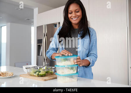 La donna in cucina la preparazione di alta farina proteica e la messa di porzioni in contenitori in plastica Foto Stock