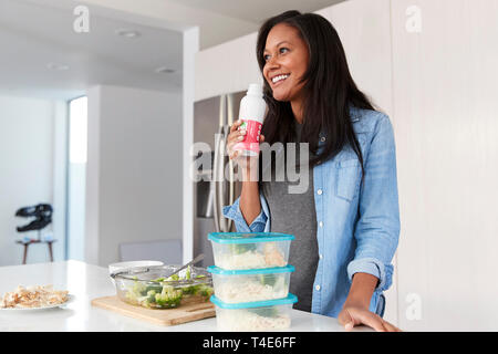La donna in cucina la preparazione di pasto sano bere Protein Shake da bottiglia