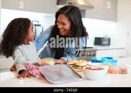 La figlia in cucina a casa madre aiuta a rendere sano il pranzo al sacco Foto Stock