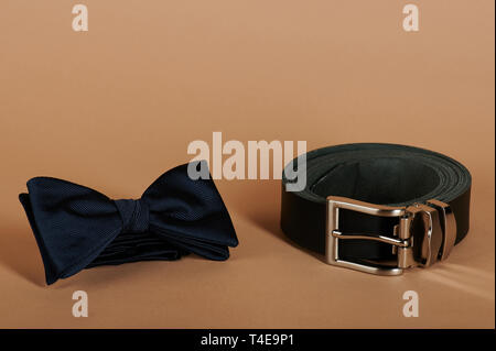 Blue bow tie e cintura nera su sfondo beige vista ravvicinata Foto Stock