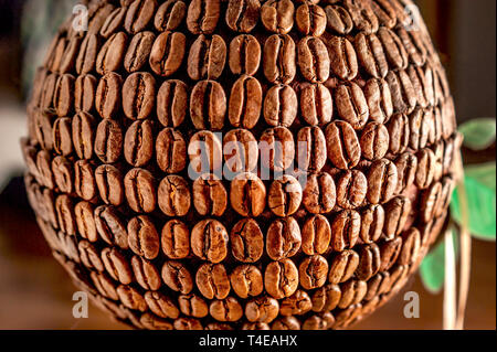 I chicchi di caffè palla. Foglie verdi in background. Mondo del Caffè, caffè pianeta concetto. Foto Stock