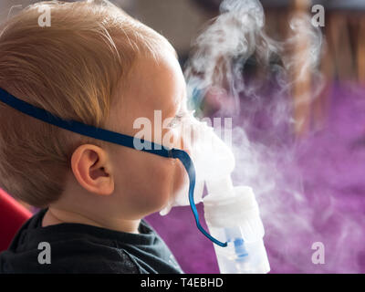 Piccolo kid rendendo inalazione con mascherina di ossigeno Foto Stock