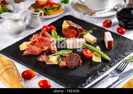 Varietà di salumi, salsicce e bacon servita su una scheda di ardesia presso il ristorante in tabella Foto Stock