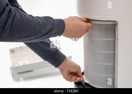 Una mano d'uomo girando un depuratore d'aria del filtro in uno nuovo. Foto Stock