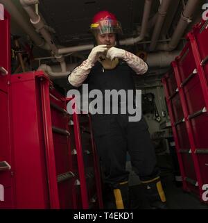 NEWPORT NEWS, Va. (27 marzo 2019) dello scafo tecnico di manutenzione Fireman James Svizz, da Hannover, Pennsylvania, assegnato alla USS Gerald Ford (CVN 78) dipartimento di ingegneria, fibbie una lotta antincendio casco durante un controllo del danno trapano. Ford è attualmente in fase di post-shakedown disponibilità presso Huntington Ingalls Industries-Newport News la costruzione navale. Foto Stock