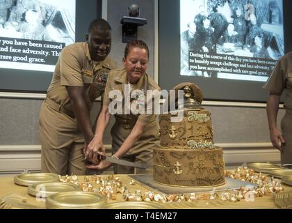 MILLINGTON, Tennessee (1 aprile 2019) Direttore Tecnico dei sistemi informativi aziendali Demarcus Frumento, sinistra e Senior Chief Navy Consigliere Rebecca Rein tagliare la torta cerimoniale durante il chief petty officer celebrazione di compleanno a Navy assunzione di comando. La giornata di oggi segna il 126compleanno del chief petty officer rank. Foto Stock