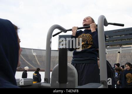 ANN Arbor, MI. (31 marzo 2019) - aspiranti guardiamarina partecipare ad un pull-up clinic durante un 'grande casa PT' sessione al Michigan Stadium come parte delle donne in servizio navale simposio ospitato dalla Università del Michigan riserva navale ufficiali di formazione unità di corpo. Questo evento è stato tenuto in collaborazione con gli Stati Uniti La marina di osservazione di storia delle donne al mese e ha fornito oltre 150 aspiranti guardiamarina da unità attraverso il paese con la possibilità di interagire e imparare dai dirigenti di sesso femminile che serve tutta la flotta. Foto Stock