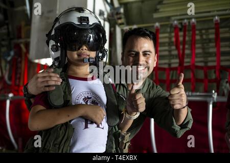 Stati Uniti Marine Corps Sgt. Alberto RUIZ II in posa per una foto con uno studente di bato Sapang scuola elementare come egli cerca su KC-130J Super Hercules apparecchiature di volo durante l'esercizio Balikatan a Clark Air Base, Filippine, Aprile 6, 2019. Balikatan è un esercizio annuale tra gli Stati Uniti e le Filippine e proviene da una frase Tagalog significato houlder "a spalla", che rappresenta la relazione tra i due paesi. L'esercizio promuove la sicurezza regionale e gli sforzi umanitari per Stati Uniti alleati e partner. Ruiz, un Murrietta, California native, è un crewmaster con antenna Marine Refueler Foto Stock