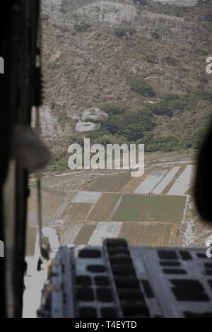 Rifornimento militare cargo scenda al di fuori di un KC-130J Super Ercole da antenna Marine Refueler squadrone di trasporto 152 oltre il colonnello Ernesto Ravina Air Base, Filippine, 8 aprile 2019, durante l'esercizio Balikatan. Balikatan è un esercizio annuale tra gli Stati Uniti e le Filippine e proviene da una frase Tagalog significato houlder "a spalla", che rappresenta la relazione tra i due paesi. L'esercizio promuove la sicurezza regionale e gli sforzi umanitari per Stati Uniti alleati e partner. Foto Stock