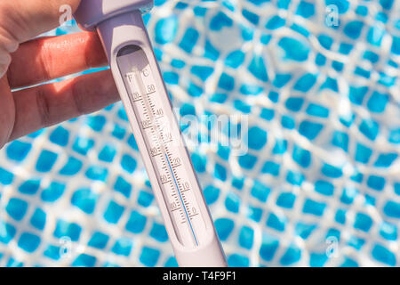 Misurare la temperatura dell' acqua in piscina con un termometro Foto Stock