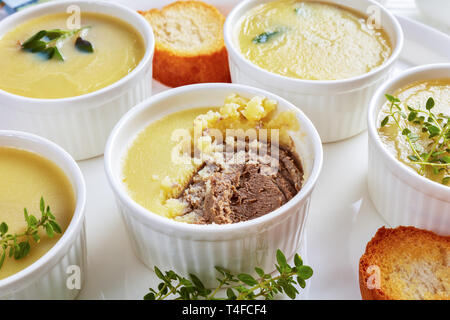 In casa ultra fluide di fegato di pollo pate con erbe aromatiche, cognac e burro in ramekins su un piatto di portata con le fette biscottate di baguette, ricetta francese, visualizzare f Foto Stock