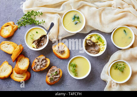 In casa ultra fluide di fegato di pollo pate con erbe aromatiche, cognac e burro in ramekins su un tavolo in cemento con fette biscottate di baguette, ricetta francese, Foto Stock