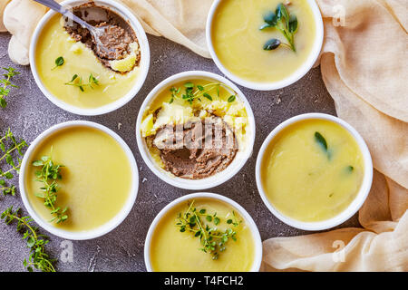 In casa di velluto di seta liscia di fegato di pollo pate con erbe aromatiche, cognac e burro in ramekins su un tavolo in cemento con fette biscottate di baguette, francese Foto Stock