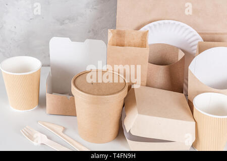 Eco-friendly utensili monouso realizzato in legno di bambù e carta su marmo bianco dello sfondo. Cucchiai drappeggiato, forcella, coltelli, piastra con bicchieri di carta. Chiudere u Foto Stock